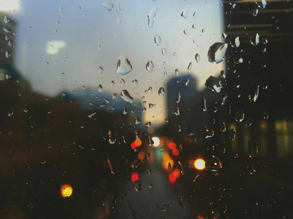 Rain drops on a window with a blurred city view